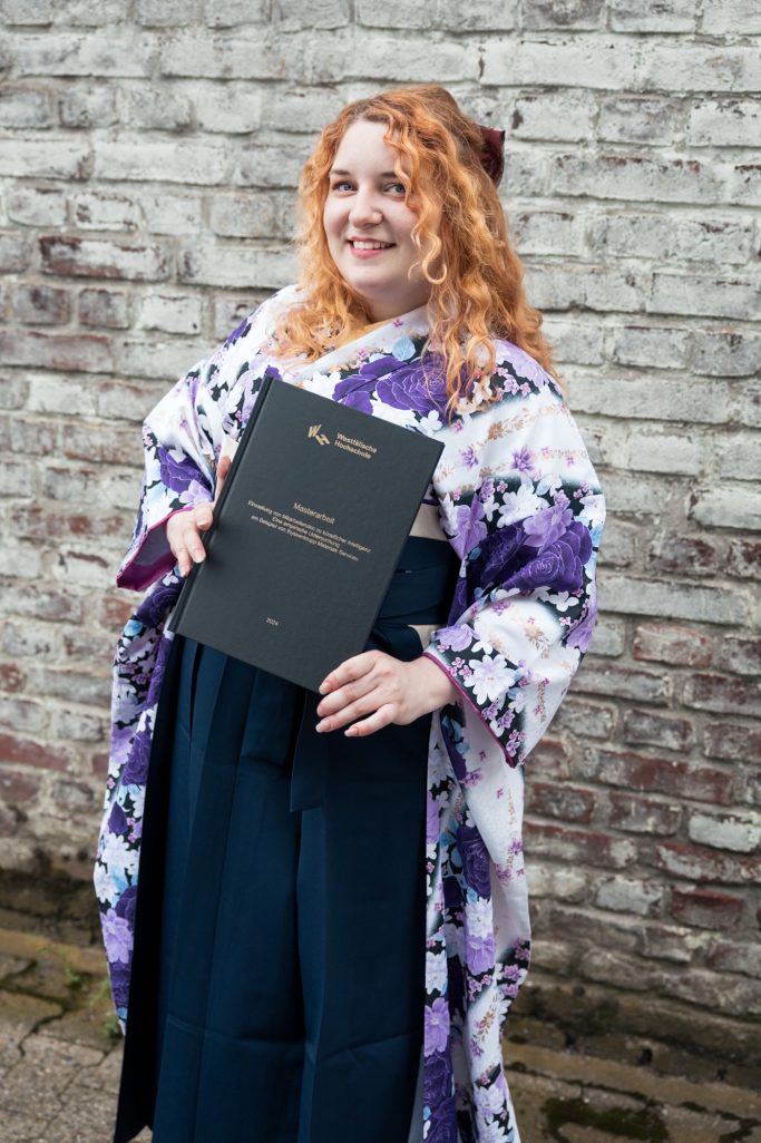 Frau in traditioneller Kleidung hält stolz ein Abschlusszeugnis.