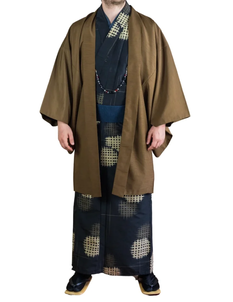 Alltagskimono für Männer Eine männlich gelesene Person in einem traditionellen Kimono, begleitet von einer langen, braunen Haori Jacke.