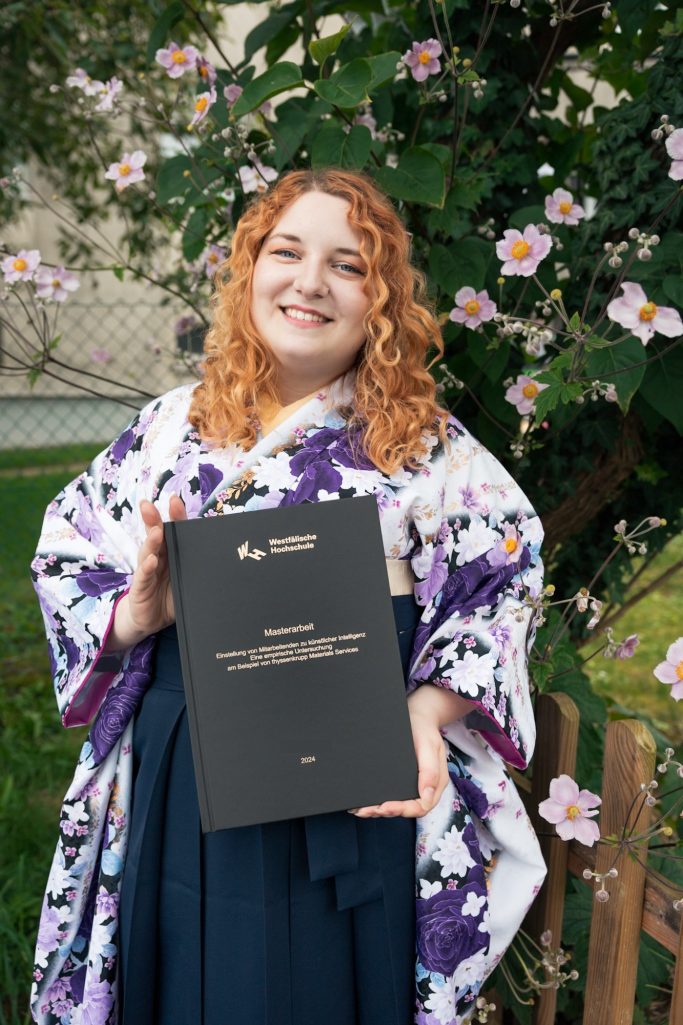 Junge Frau in Kimono hält stolz ihr Abschlusszeugnis vor blühenden Pflanzen.